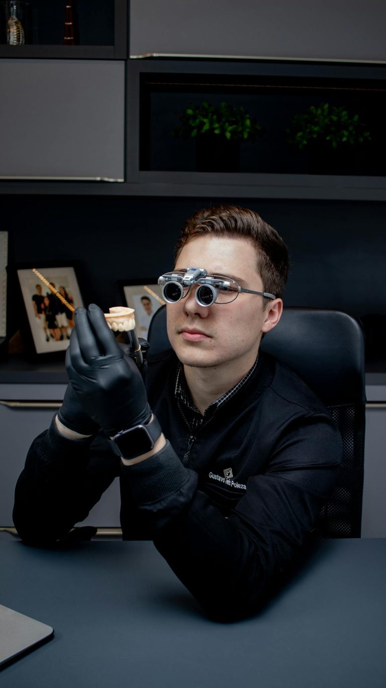 A dentist in a modern office examining a dental prosthetic with precision tools.