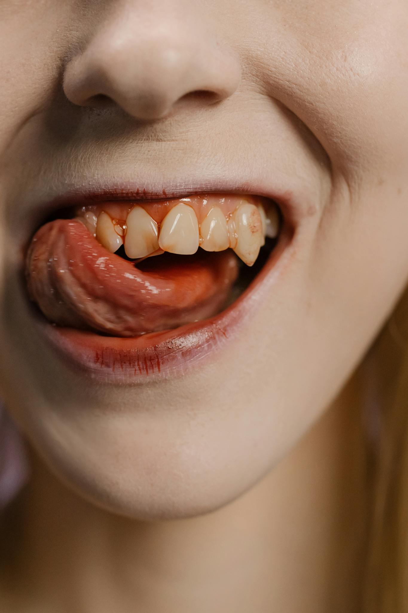 Detailed shot focusing on a mouth with visible fangs and tongue, evoking a vampire aesthetic.